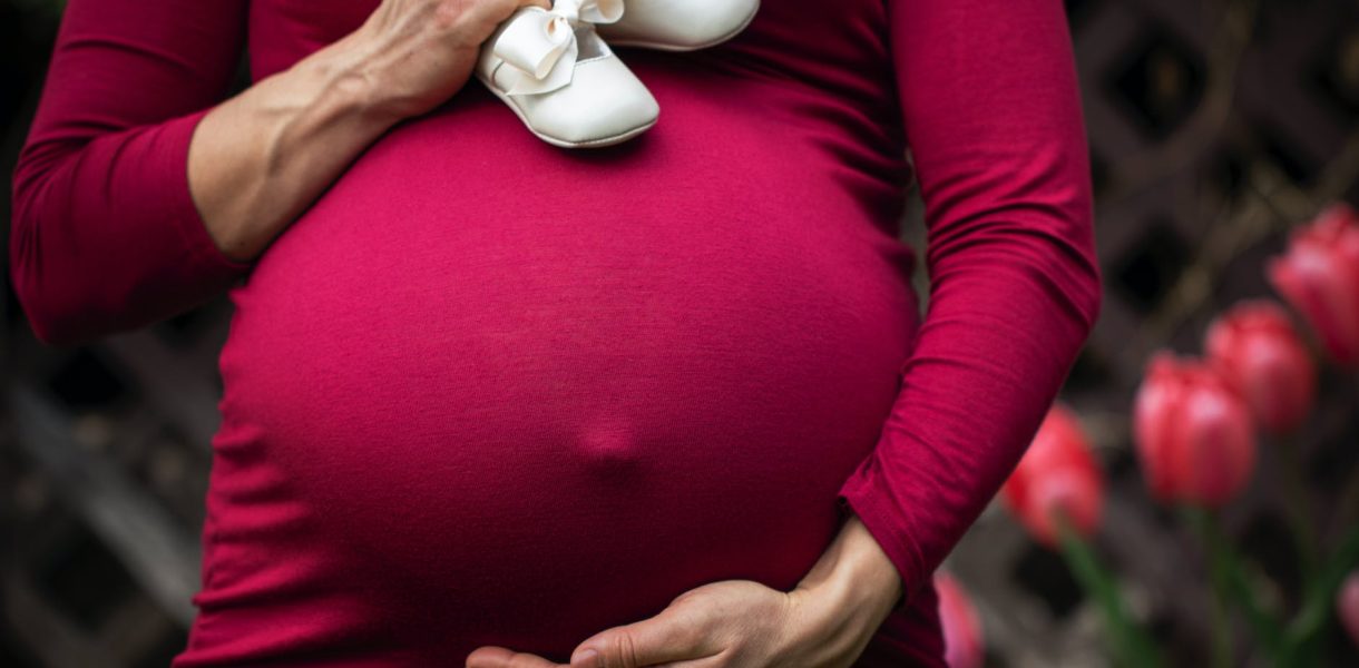 pregnant woman holding baby s shoes