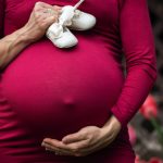 pregnant woman holding baby s shoes